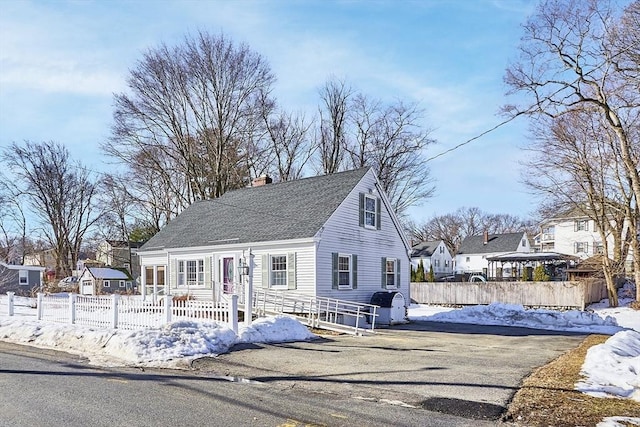 view of front of house featuring a chimney, fence, and roof with shingles