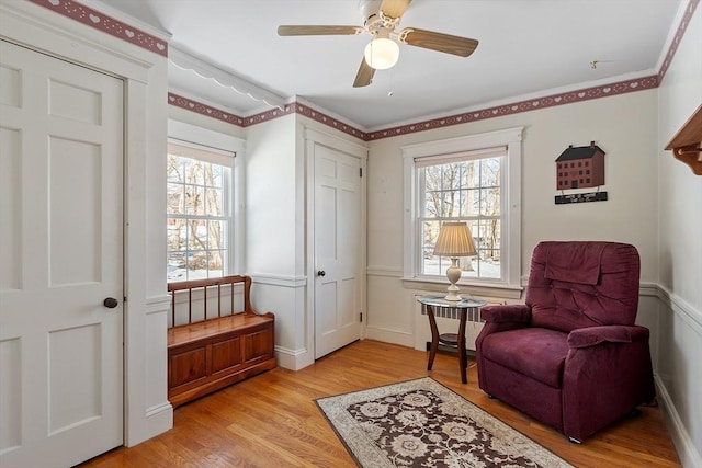 living area with ceiling fan, radiator, a healthy amount of sunlight, and light wood-style floors