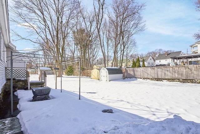 yard layered in snow with a storage unit, an outdoor structure, and a fenced backyard