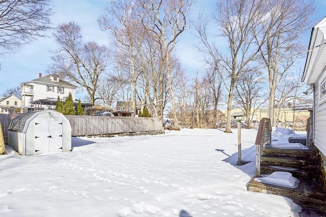 yard covered in snow with an outbuilding, fence, and a storage unit