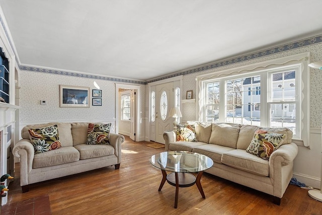 living area with a wainscoted wall, wood finished floors, and wallpapered walls