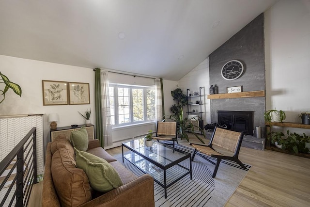 living area featuring a fireplace with raised hearth, high vaulted ceiling, a baseboard radiator, and wood finished floors