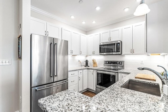 kitchen featuring sink, stainless steel appliances, white cabinets, and decorative light fixtures