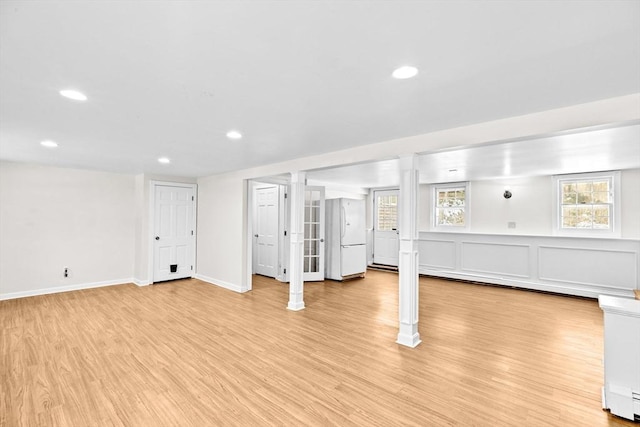 basement featuring white refrigerator and light hardwood / wood-style flooring