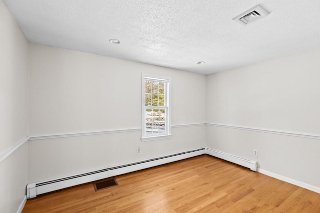 unfurnished room with a baseboard heating unit, hardwood / wood-style floors, and a textured ceiling