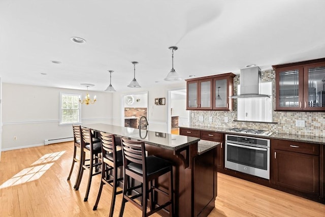 kitchen featuring appliances with stainless steel finishes, dark brown cabinetry, and wall chimney exhaust hood