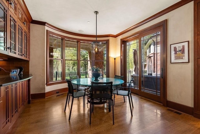 dining room featuring crown molding, a wealth of natural light, and dark hardwood / wood-style flooring