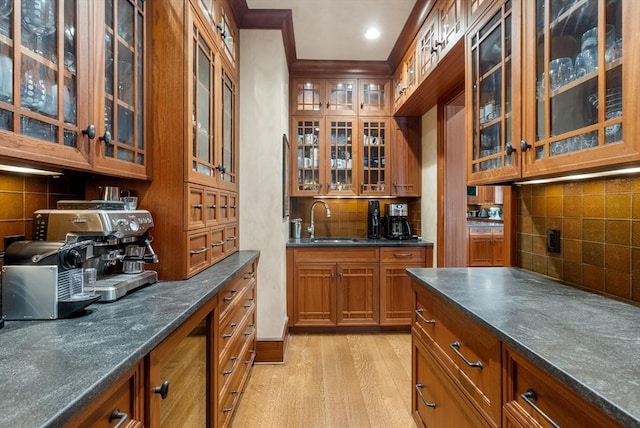 bar featuring sink, decorative backsplash, and light hardwood / wood-style flooring