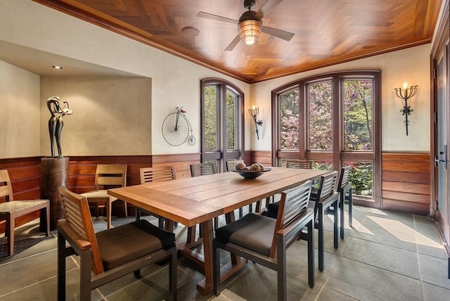 dining space with crown molding, ceiling fan, and wood walls