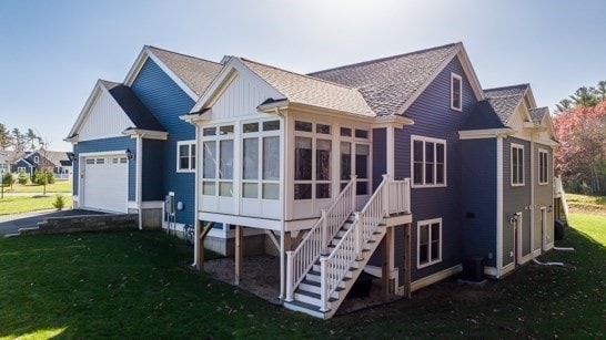 back of house featuring a garage, a lawn, and a sunroom