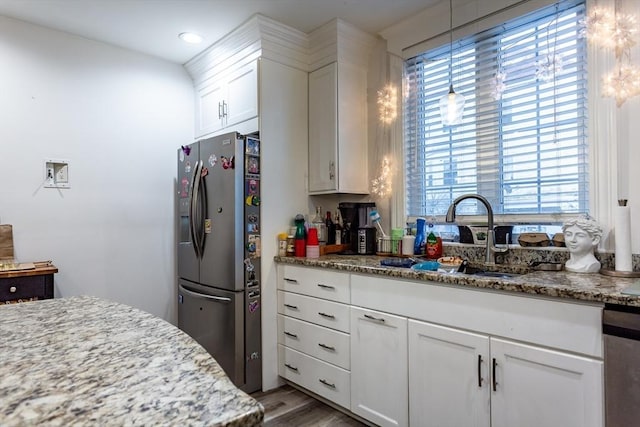 kitchen with sink, stainless steel fridge, light hardwood / wood-style flooring, white cabinetry, and light stone counters