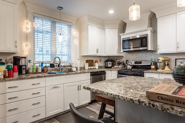 kitchen featuring hanging light fixtures, sink, white cabinets, and appliances with stainless steel finishes