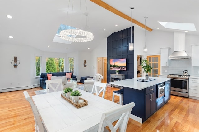 kitchen featuring hanging light fixtures, white cabinets, stainless steel appliances, and wall chimney range hood