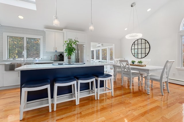 kitchen featuring pendant lighting, white cabinets, light hardwood / wood-style floors, a kitchen island, and lofted ceiling