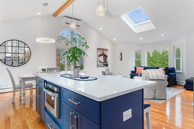 kitchen with blue cabinets, an AC wall unit, vaulted ceiling with skylight, decorative light fixtures, and light hardwood / wood-style floors