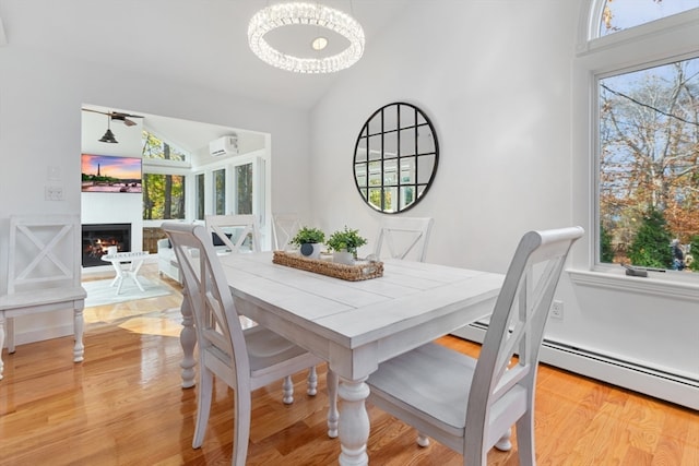 dining room featuring ceiling fan with notable chandelier, light wood-type flooring, and lofted ceiling