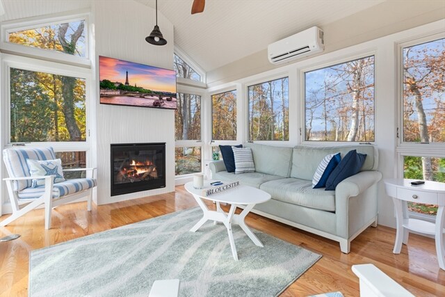 sunroom featuring a wall mounted air conditioner, plenty of natural light, a fireplace, and vaulted ceiling