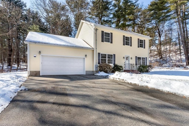 colonial inspired home with a garage and aphalt driveway