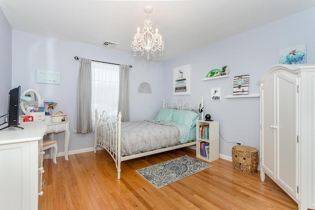 bedroom featuring a chandelier, light wood-type flooring, visible vents, and baseboards