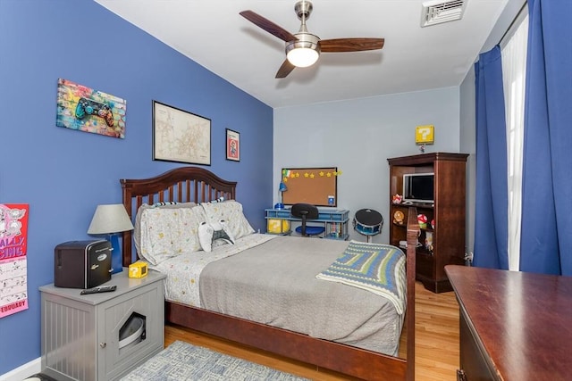 bedroom with a ceiling fan, visible vents, and wood finished floors