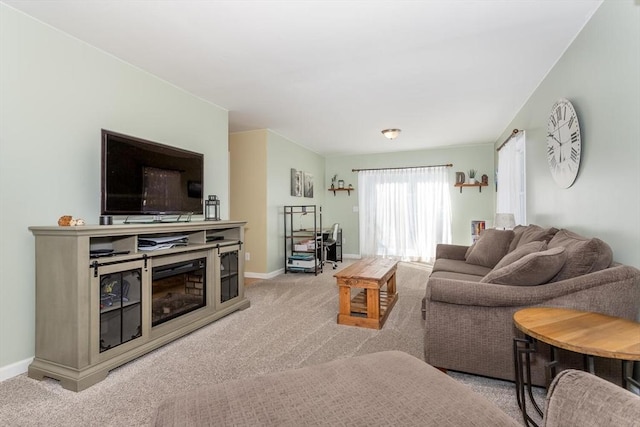 living room featuring baseboards, a glass covered fireplace, and light colored carpet