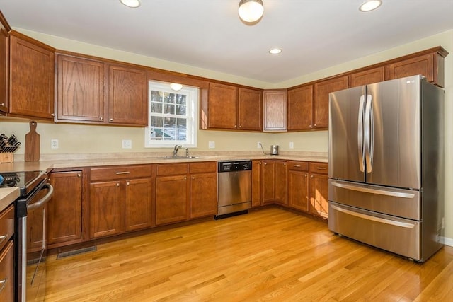 kitchen with light wood-style flooring, recessed lighting, stainless steel appliances, a sink, and light countertops