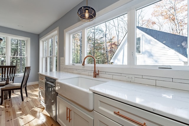 kitchen featuring light stone countertops, white cabinets, sink, light hardwood / wood-style flooring, and dishwasher