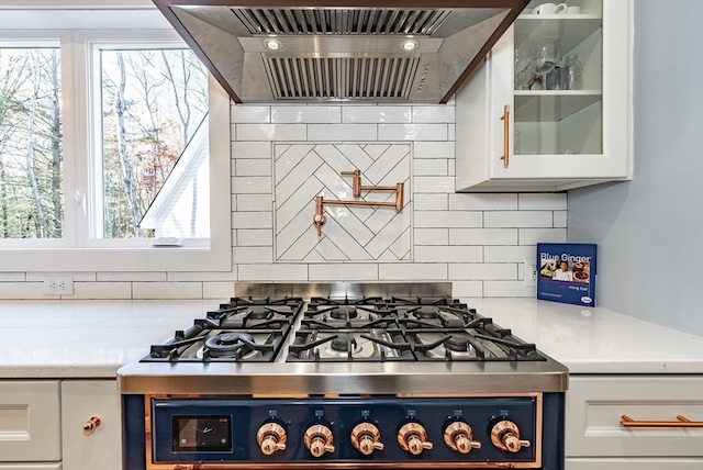 kitchen featuring ventilation hood, plenty of natural light, white cabinets, and stainless steel stove