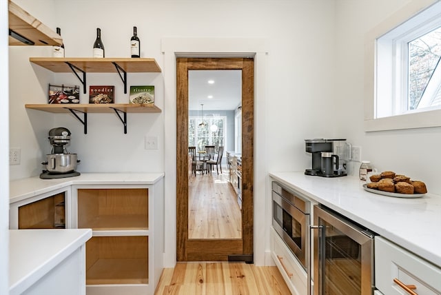 bar featuring light stone countertops, light hardwood / wood-style flooring, wine cooler, and white cabinets