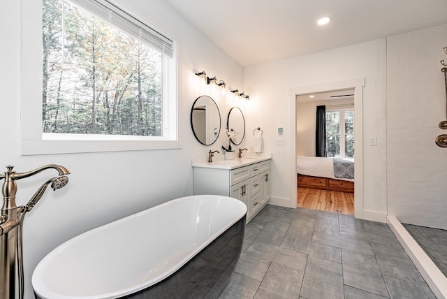 bathroom with a bathing tub, vanity, hardwood / wood-style flooring, and a wealth of natural light