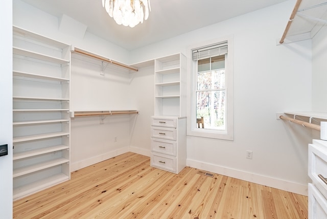 walk in closet with wood-type flooring and a chandelier