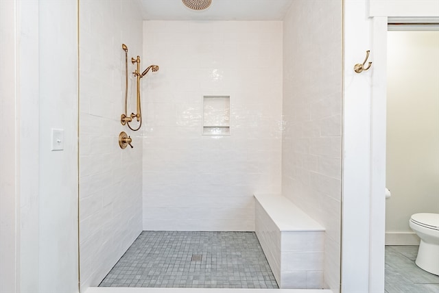 bathroom featuring tiled shower and toilet