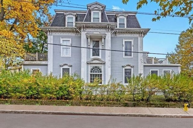 victorian home featuring a balcony and mansard roof