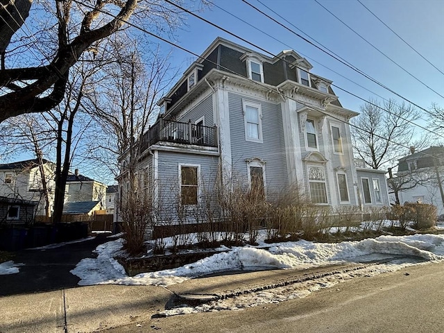 snow covered property featuring a balcony and mansard roof