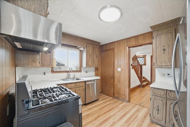 5 Ellington Rd, Quincy, MA 02171 - kitchen with stainless steel appliances, range hood, a sink, brown cabinets, and wood walls