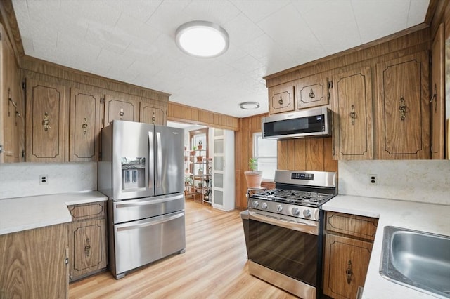 5 Ellington Rd, Quincy, MA 02171 - kitchen featuring appliances with stainless steel finishes, brown cabinets, light wood finished floors, light countertops, and wood walls
