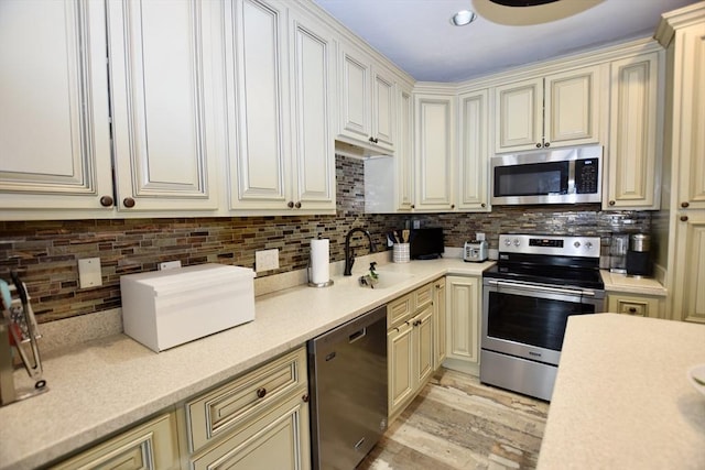 kitchen featuring a sink, light countertops, appliances with stainless steel finishes, light wood-type flooring, and decorative backsplash