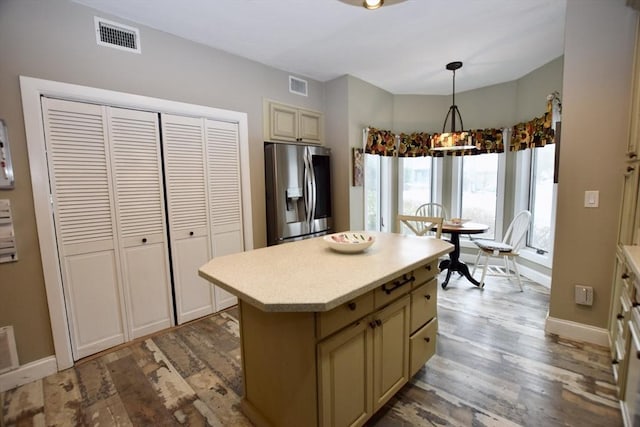 kitchen featuring visible vents, light countertops, hanging light fixtures, a center island, and stainless steel fridge