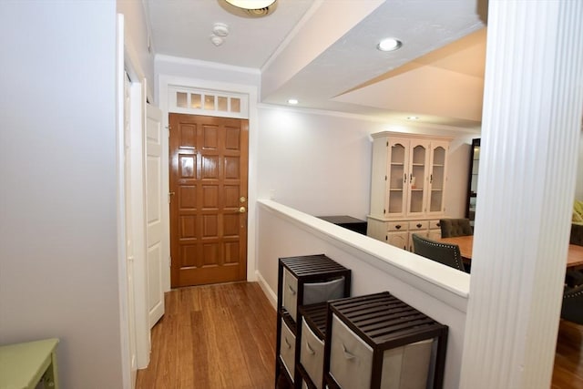 hallway with light wood-type flooring, an upstairs landing, ornamental molding, and recessed lighting