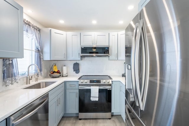 kitchen featuring tasteful backsplash, light wood-style flooring, stainless steel appliances, a sink, and recessed lighting