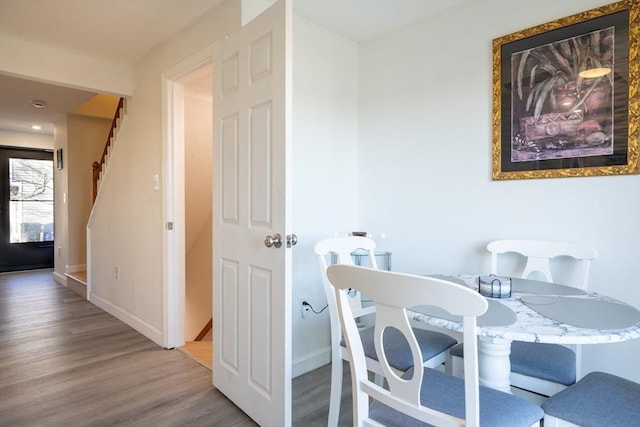 dining area with stairway, baseboards, and wood finished floors