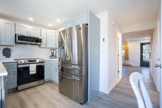 kitchen with stainless steel appliances, light wood-style floors, light countertops, and a baseboard heating unit