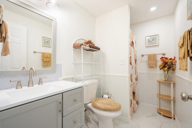 full bathroom featuring toilet, a wainscoted wall, marble finish floor, and vanity