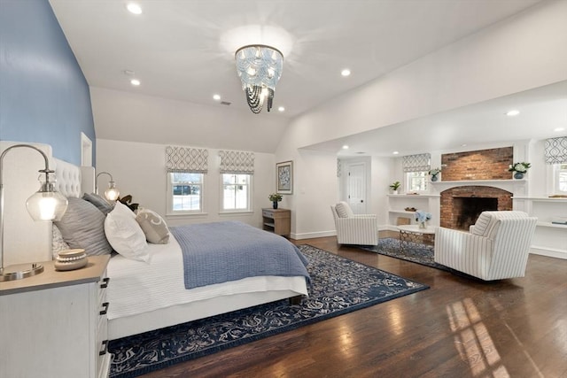 bedroom featuring dark wood-type flooring, lofted ceiling, a fireplace, and a notable chandelier