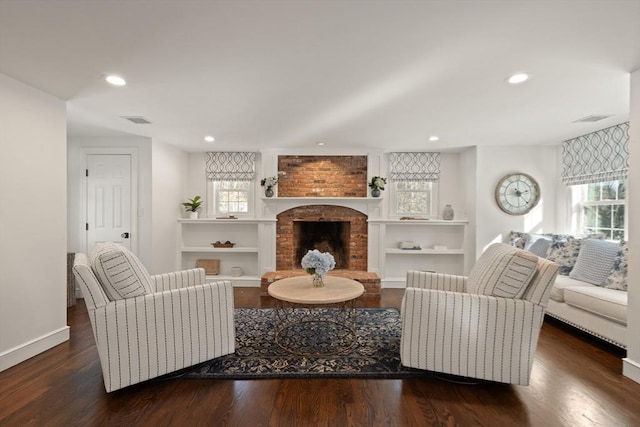 living room featuring dark wood-type flooring and a brick fireplace