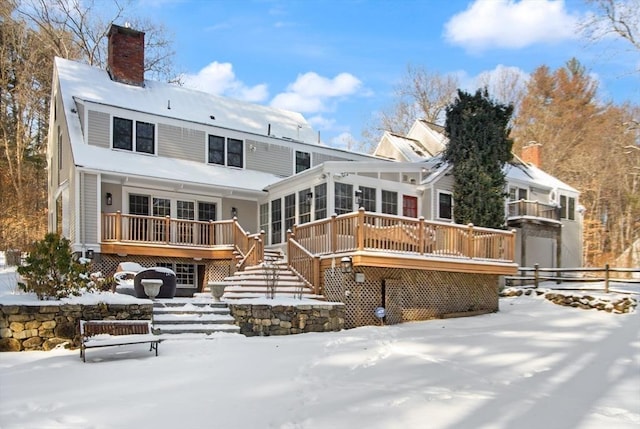 snow covered property featuring a wooden deck and a sunroom