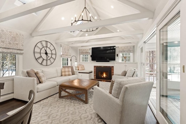 living room with lofted ceiling with beams, light wood-type flooring, a notable chandelier, and a fireplace