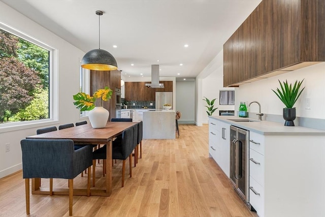 kitchen with pendant lighting, light countertops, white cabinetry, a sink, and stainless steel fridge