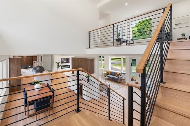 staircase with a towering ceiling and light wood-type flooring