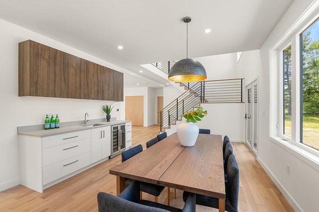 dining area featuring light wood-style floors, recessed lighting, baseboards, and stairs